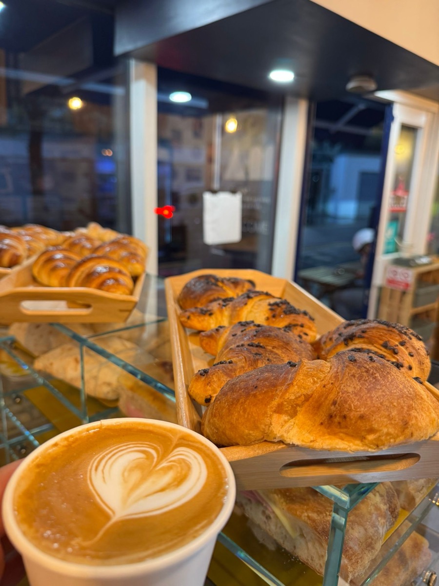 Fresh cornetti in wooden trays beside a flat white at Neama