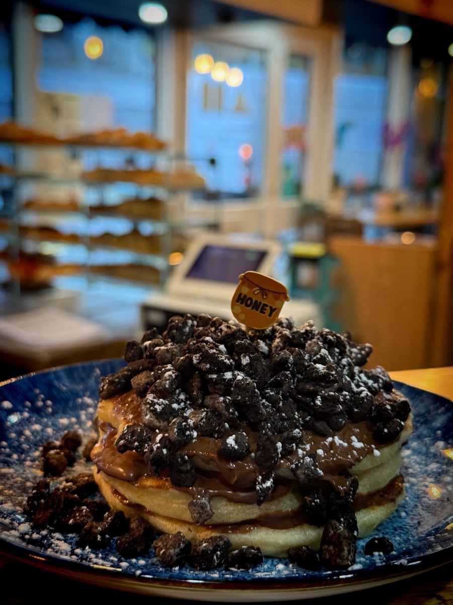 A stack of Oreo pancakes with chocolate cream on a blue plate at Neama